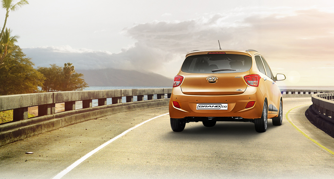 Side view of tangerine orange Grand i10 on a clear day