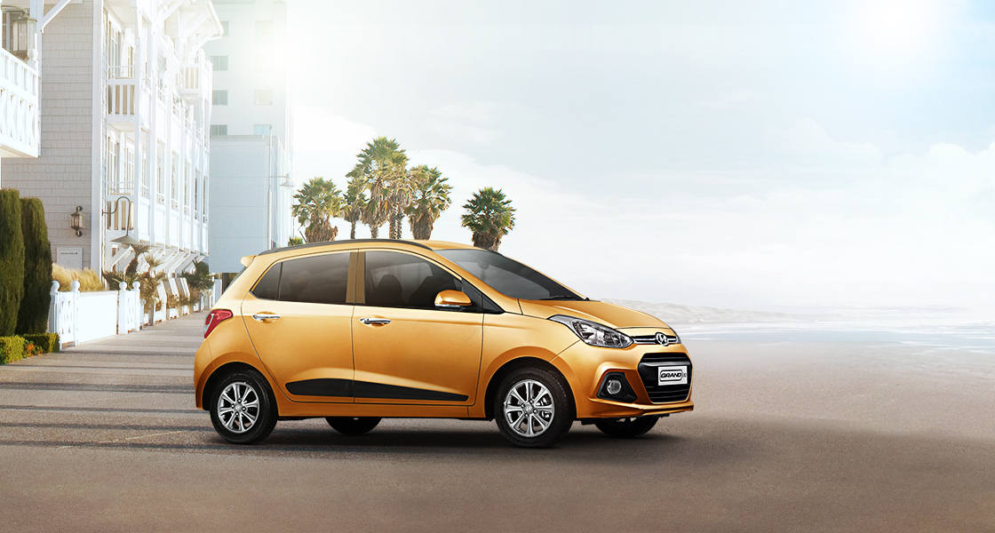 Side view of tangerine orange Grand i10 on a clear day