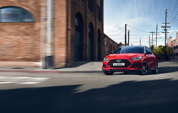 Left side rear view of red veloster driving on the road