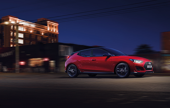 Right side view of red veloster driving on the road