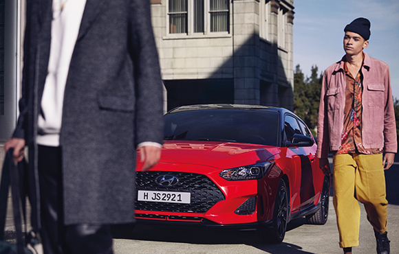 Left side front view of red veloster parking on the road