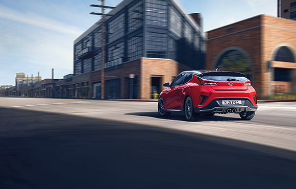 Left side view of red veloster driving on the road