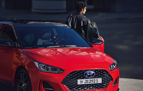 Right side front view of red veloster parking on the road