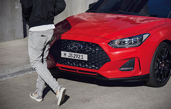 Left side front view of red veloster parking on the road