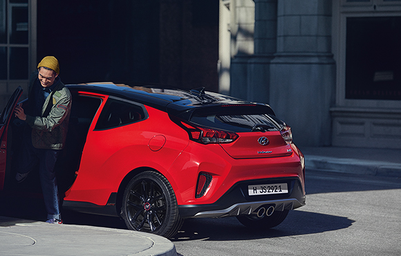 Left side rear view of red veloster parking on the road