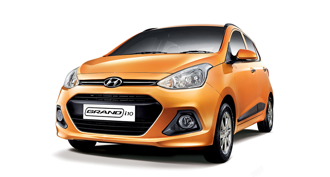 Side-front view of orange Grandi10 with lakeside view at night