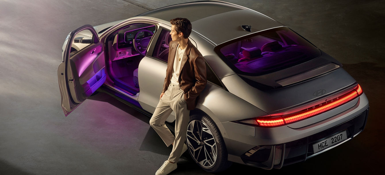 Side-front view of orange Grandi10 with lakeside view at night