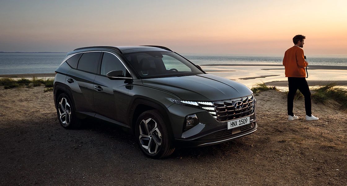 Side-front view of orange Grandi10 with lakeside view at night